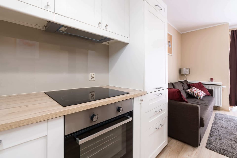 A close-up of a stovetop, white cabinets, and a kettle sitting on the counter.
