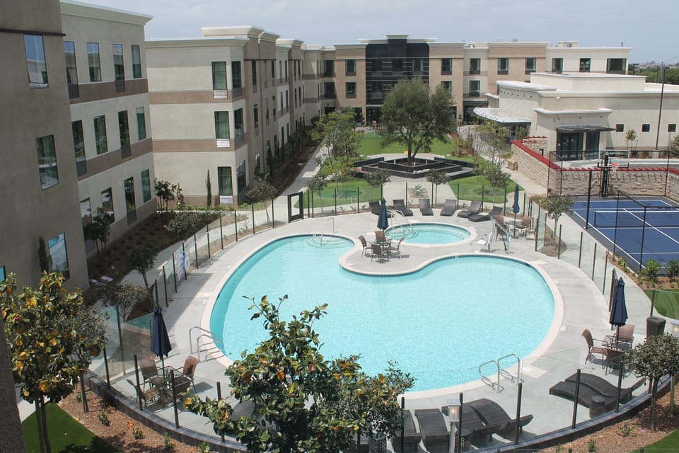 Outdoor pool with lounge chairs in sunny surroundings.