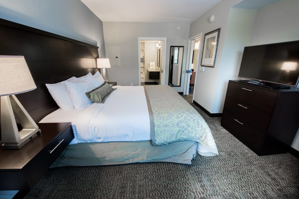Bedroom with king bed, lamps, flat-screen TV, and dresser.