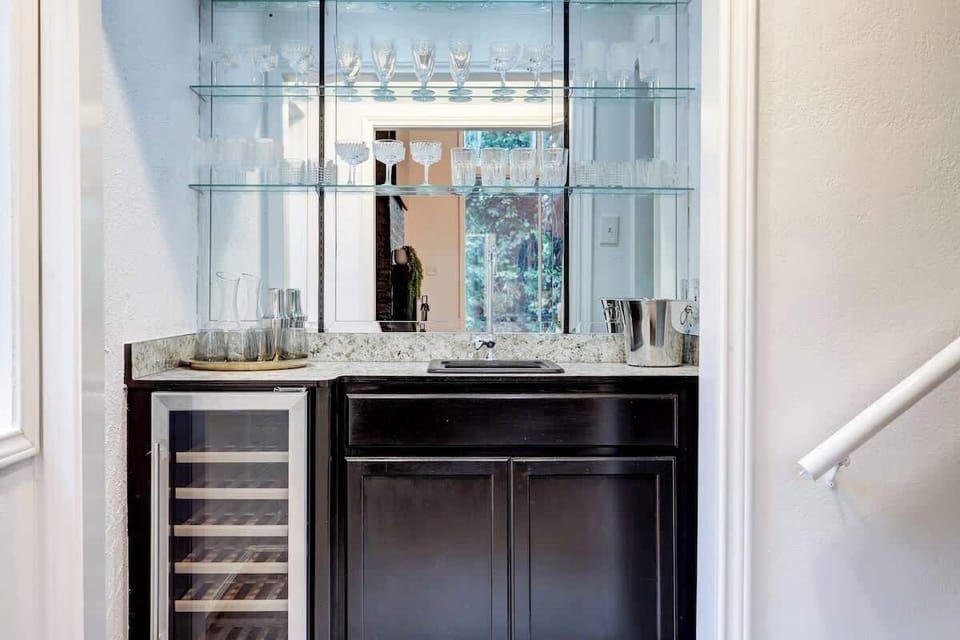 Wet bar with glassware and a wine refrigerator located adjacent to the living room - perfect for entertaining!