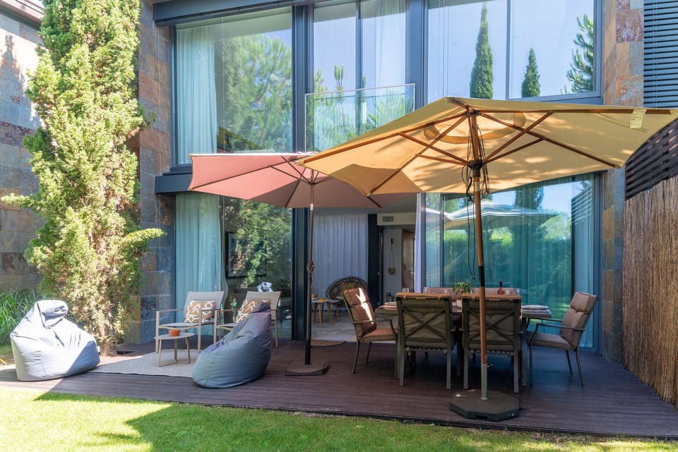Spacious wooden terrace with dining area and umbrellas — Home Six Troia, holiday villa in Grândola