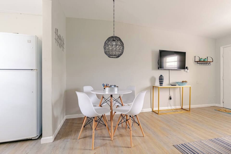 Bright dining area featuring a round table and stylish white chairs.