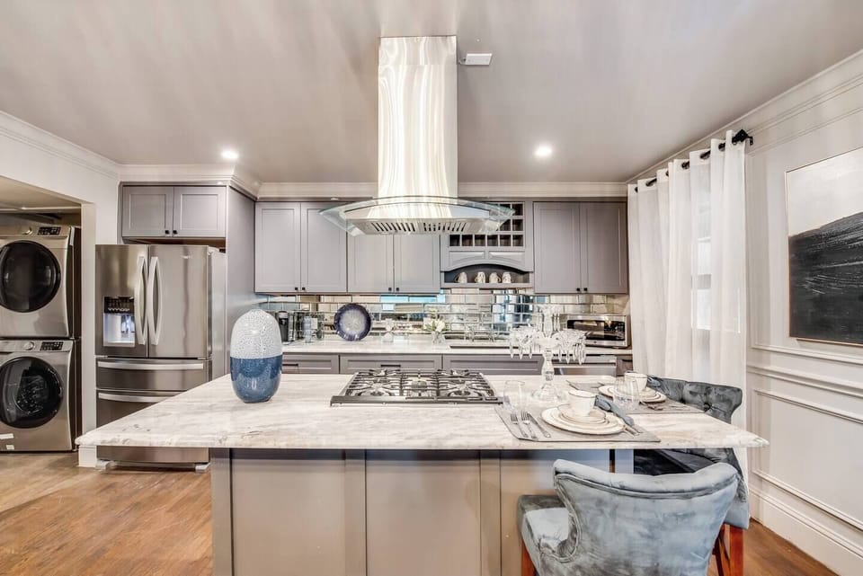 A spacious gourmet kitchen featuring a gas range, sleek stainless steel vent hood, and all the tools you need to cook and entertain with ease. 