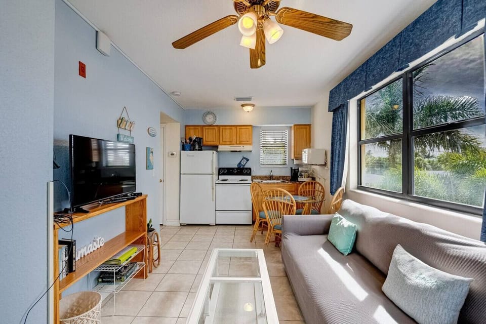 Bright living area w/ comfy seating, TV, and large windows that fill the space with natural light.