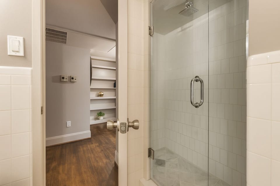Private en-suite with a glass shower and marble flooring, seamlessly blending modern luxury with timeless charm.