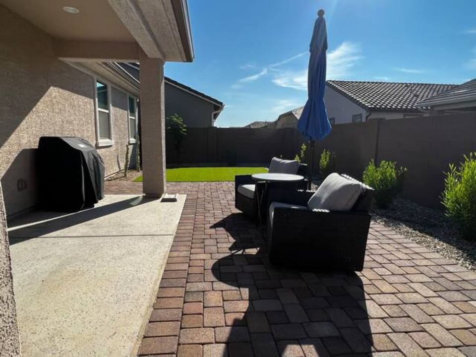 Backyard patio has seating, umbrella, natural gas grill