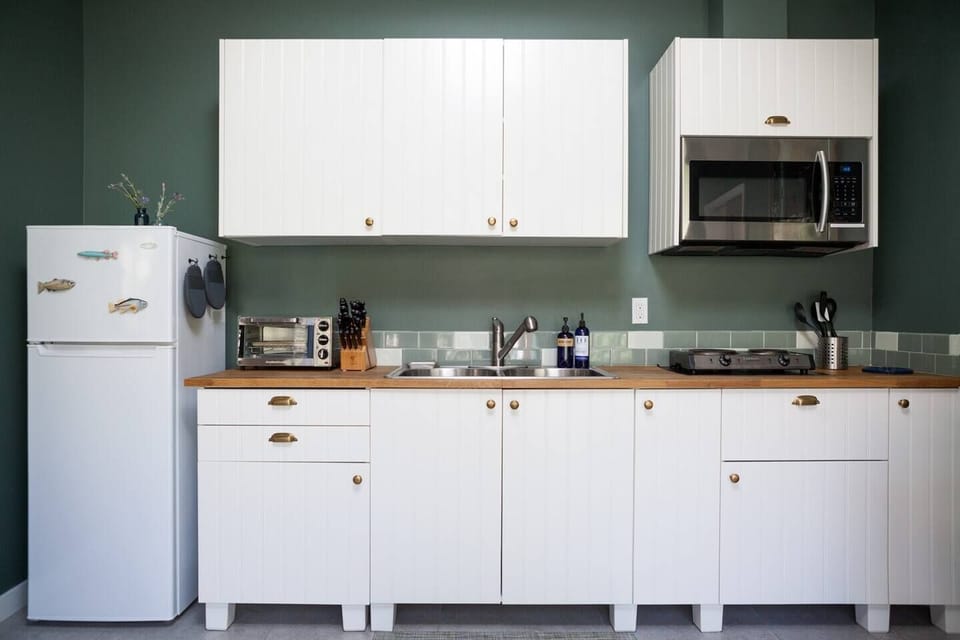 Refrigerator/freezer,  toaster oven, electric single burner, microwave, kettle, blender, grinder, cook tools, cutlery & knives. All dinnerware & serveware. Coffee/tea station with drip & pod machine, french press. Includes local roast ground coffee & pods 