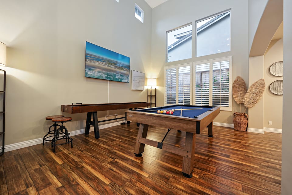 Game room features high ceilings, a pool table, shuffleboard, and giant Smart TV.