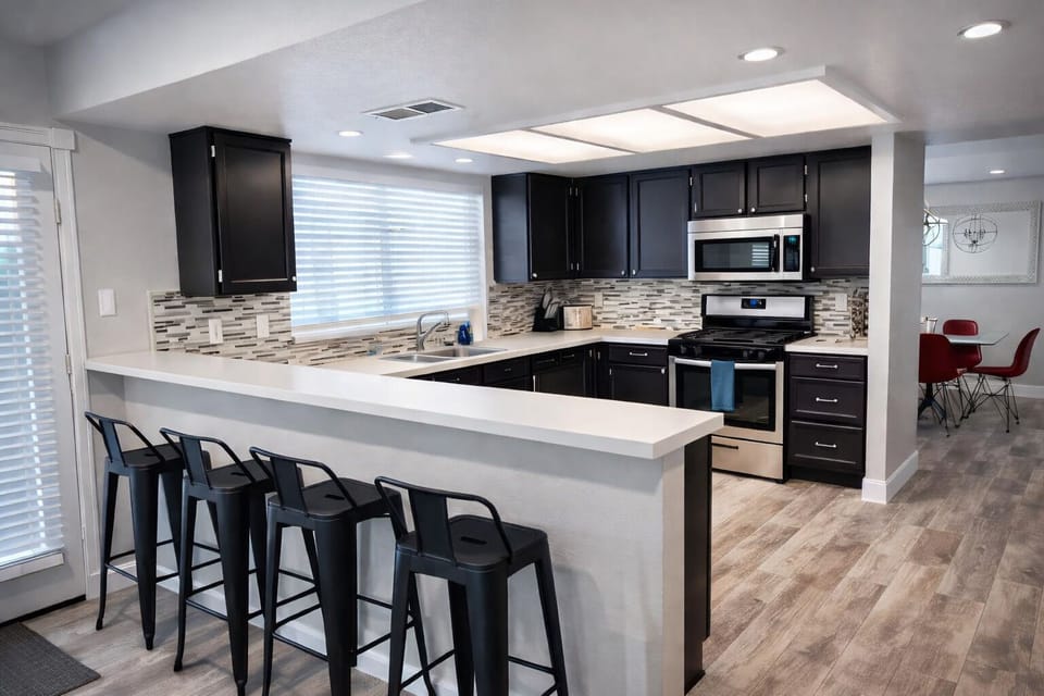 Modern chef’s kitchen with bar seating, stainless apps, open plan.