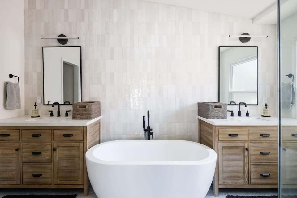 Lavish ensuite bathroom in primary bedroom, with two full sinks, bathtub, standing shower, and walk-in closet