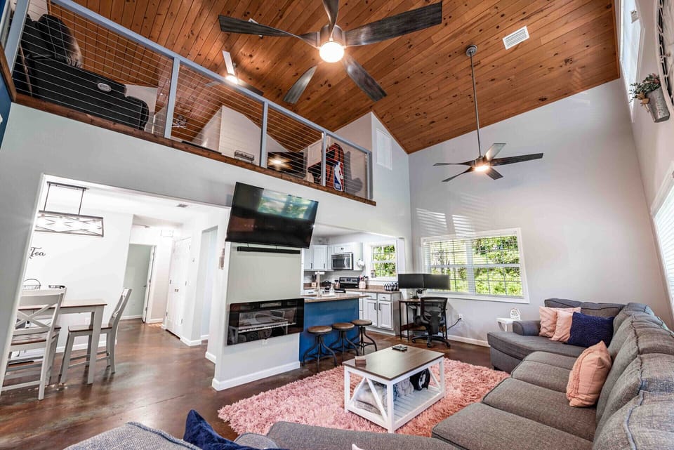 Living room with electric fireplace, smart TV, sound bar, large sofa. 