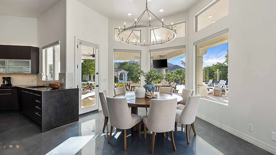 Eight-person dining table off kitchen with backyard views & luxury seating.