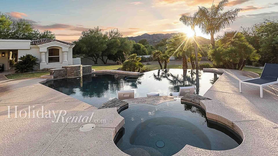 Immaculate pool and spa with sun loungers and sunset mountain views.