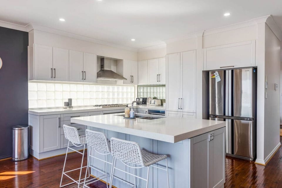 Our kitchen area is a sleek and modern space with a crisp white color scheme. The top bar table provides a convenient surface for food preparation and casual dining.