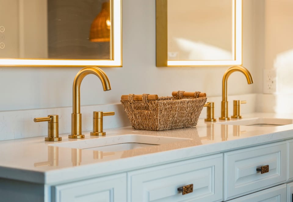 A chic double vanity with gold fixtures and soft backlighting sets the stage for a spa-like experience—because every day should start with a little luxury.