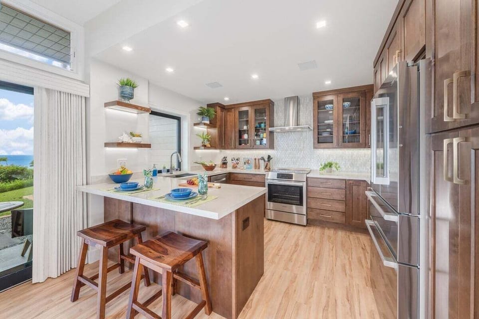 Fully remodeled kitchen featuring Bosch appliances, island bar seating, and open sightlines to the dining and living areas.