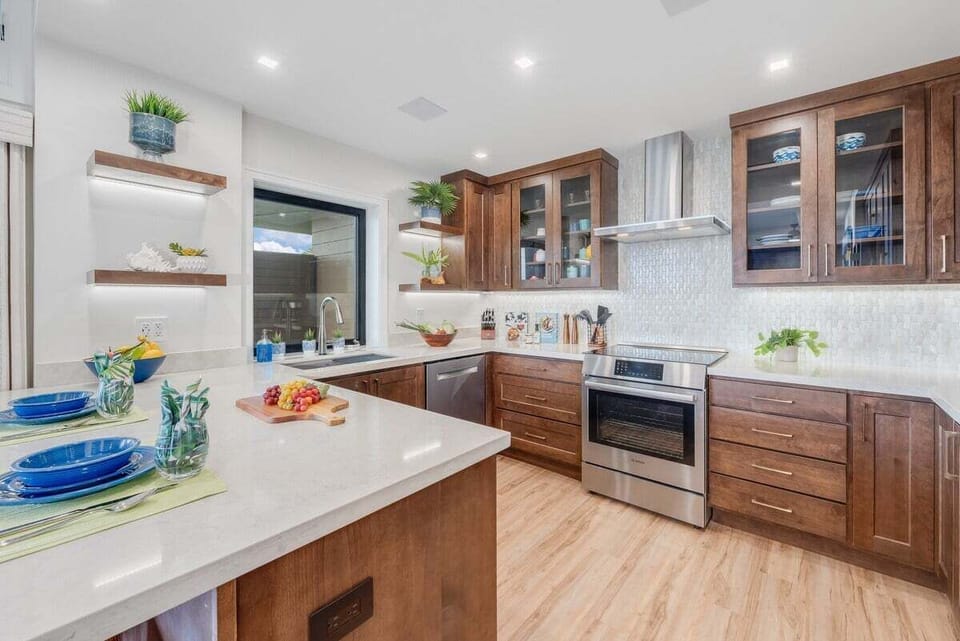 Fully remodeled kitchen with central island, Bosch appliances, stone countertops, and warm wood cabinetry in a bright open layout.