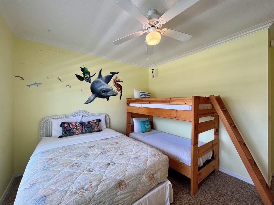 Drift off to sleep surrounded by ocean adventures in this cozy bedroom featuring a double bed and bunk bed.