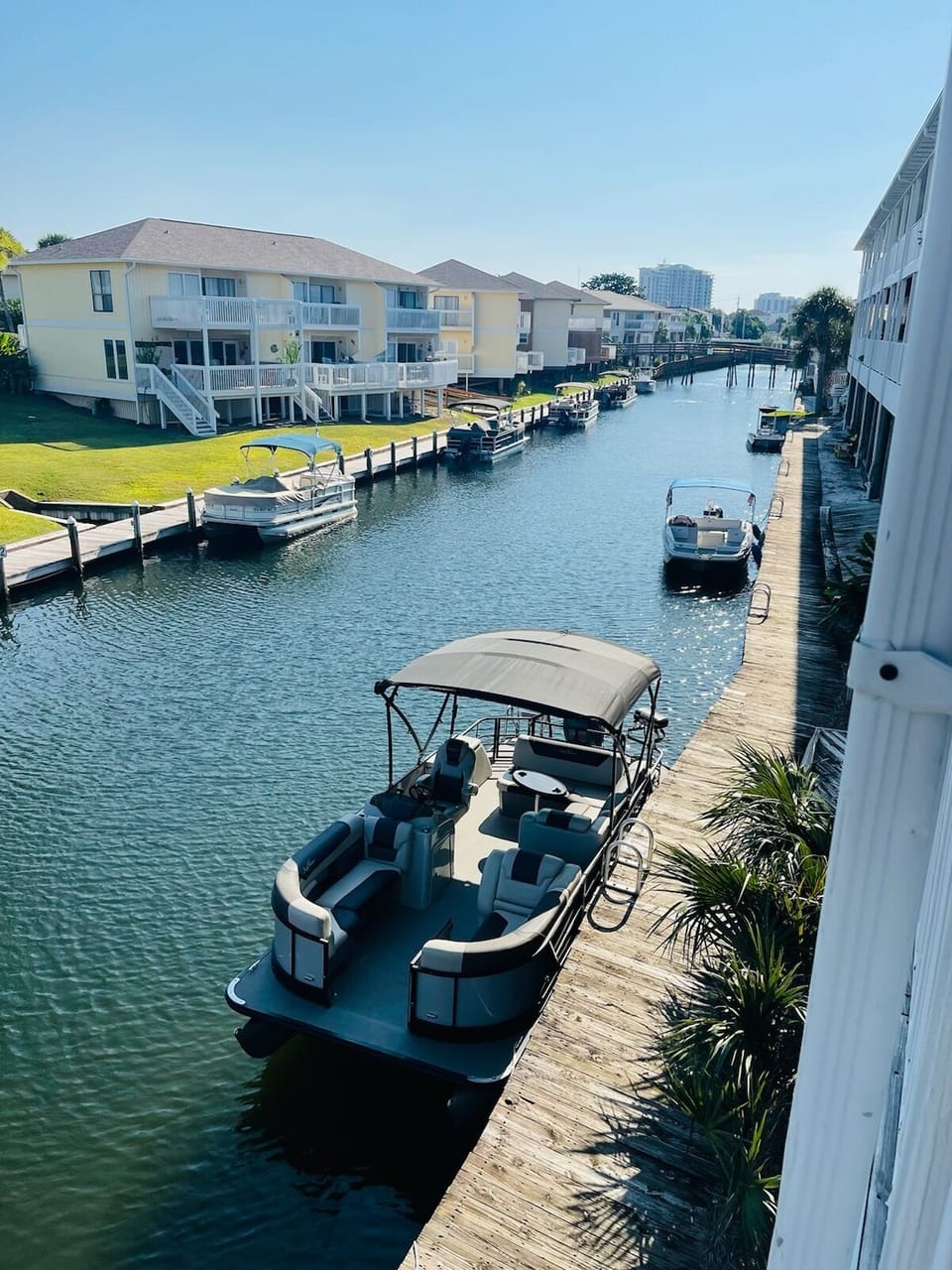 Waterfront canal view showcasing private boat docks, pontoon boats, and neighboring vacation properties in a peaceful residential marina setting.