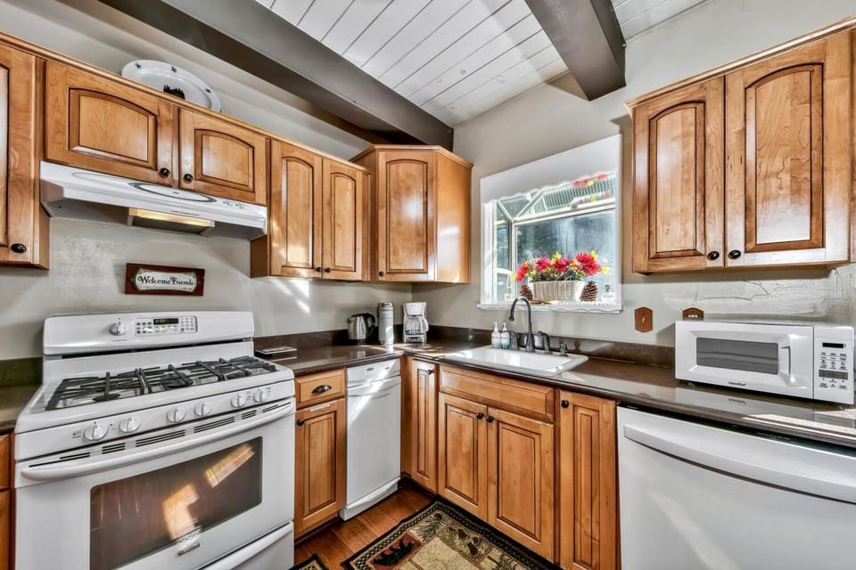 Your fully equipped kitchen awaits with warm wood cabinets, modern appliances, and charming exposed beams overhead.