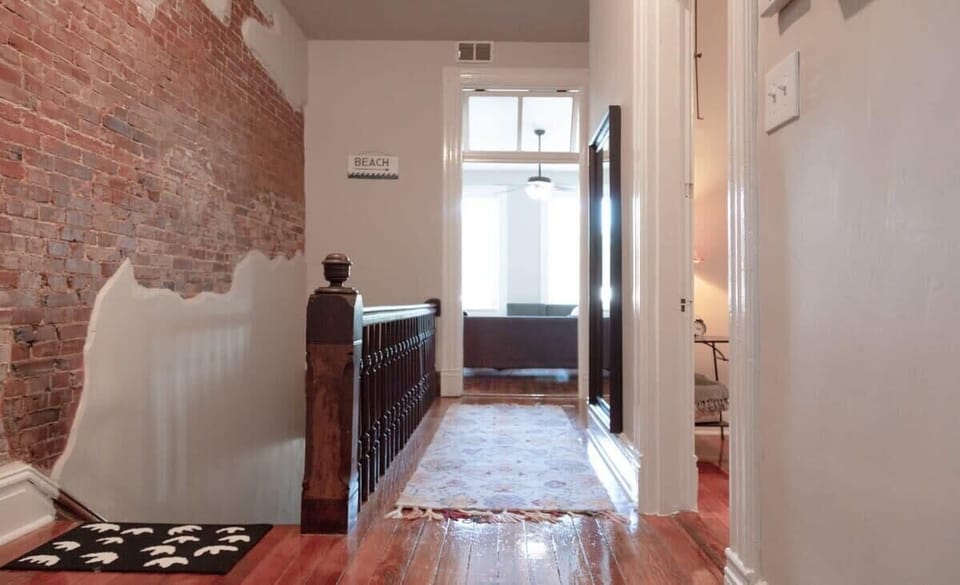 Charming upstairs hallway with original brickwork leading to bright and open living spaces. #UniqueStay 