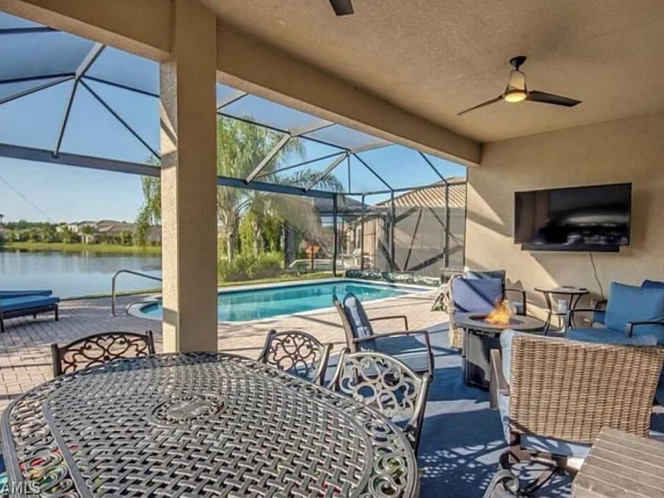 Outdoor lanai with pool, television, fire pit, and lake view