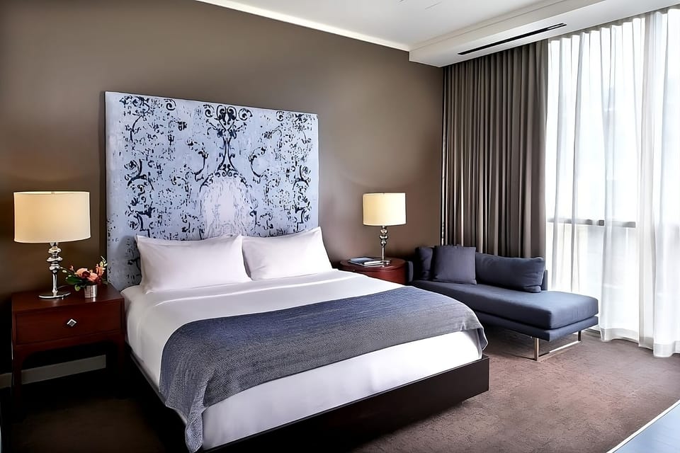 Sink into crisp linens beside soft light and city views.