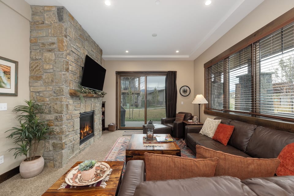 Unwind in your cozy living room featuring a stunning stone fireplace, plush sectional seating, and warm ambiance perfect for relaxing evenings.