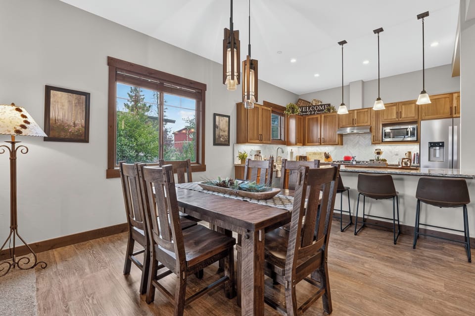 Gather around the handsome wood dining table beneath warm pendant lights, then chat at the kitchen island while preparing meals with modern appliances and ample counter space.