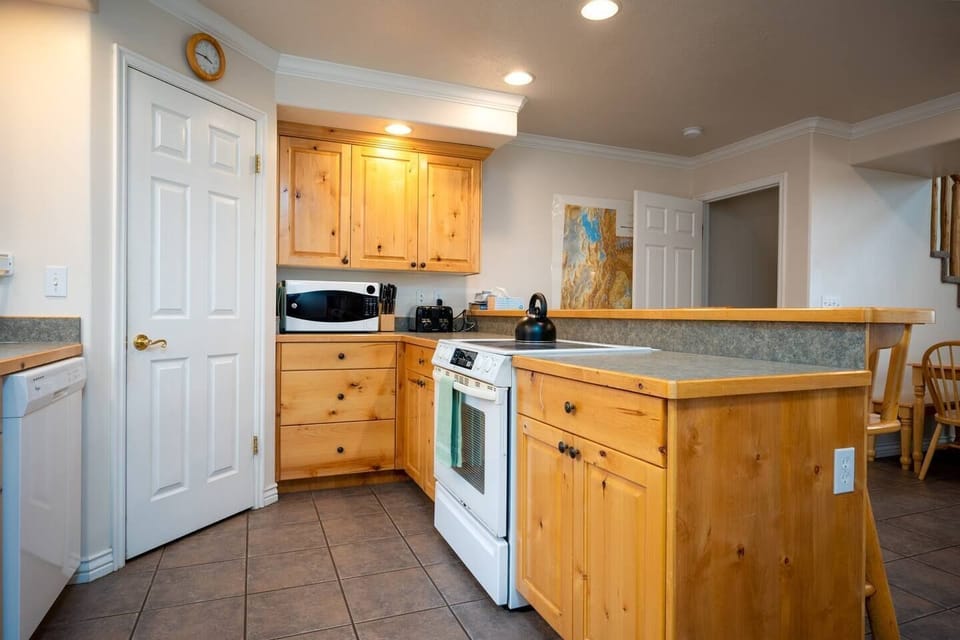 This well-equipped kitchen features an electric stove, large kettle, dishwasher, microwave, and other appliances for your convenience and culinary enjoyment.