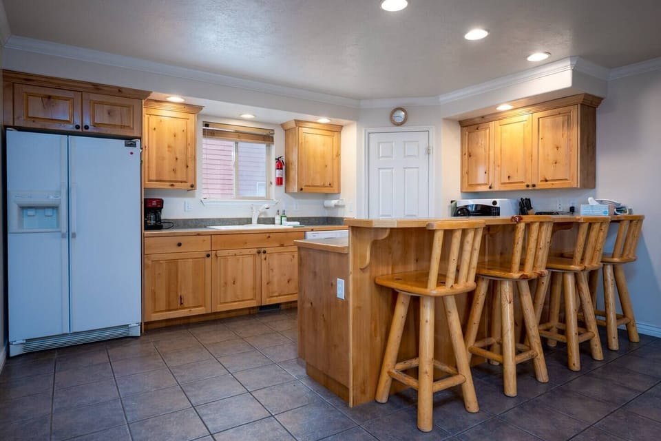 The kitchen features a breakfast bar with seating for four and is equipped with appliances, including a microwave, electric stove, and spacious refrigerator.