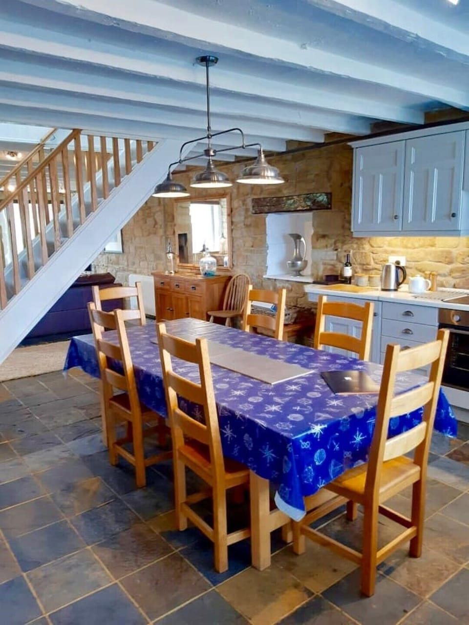 The staircase separates the kitchen from the living area, all with a slate floor