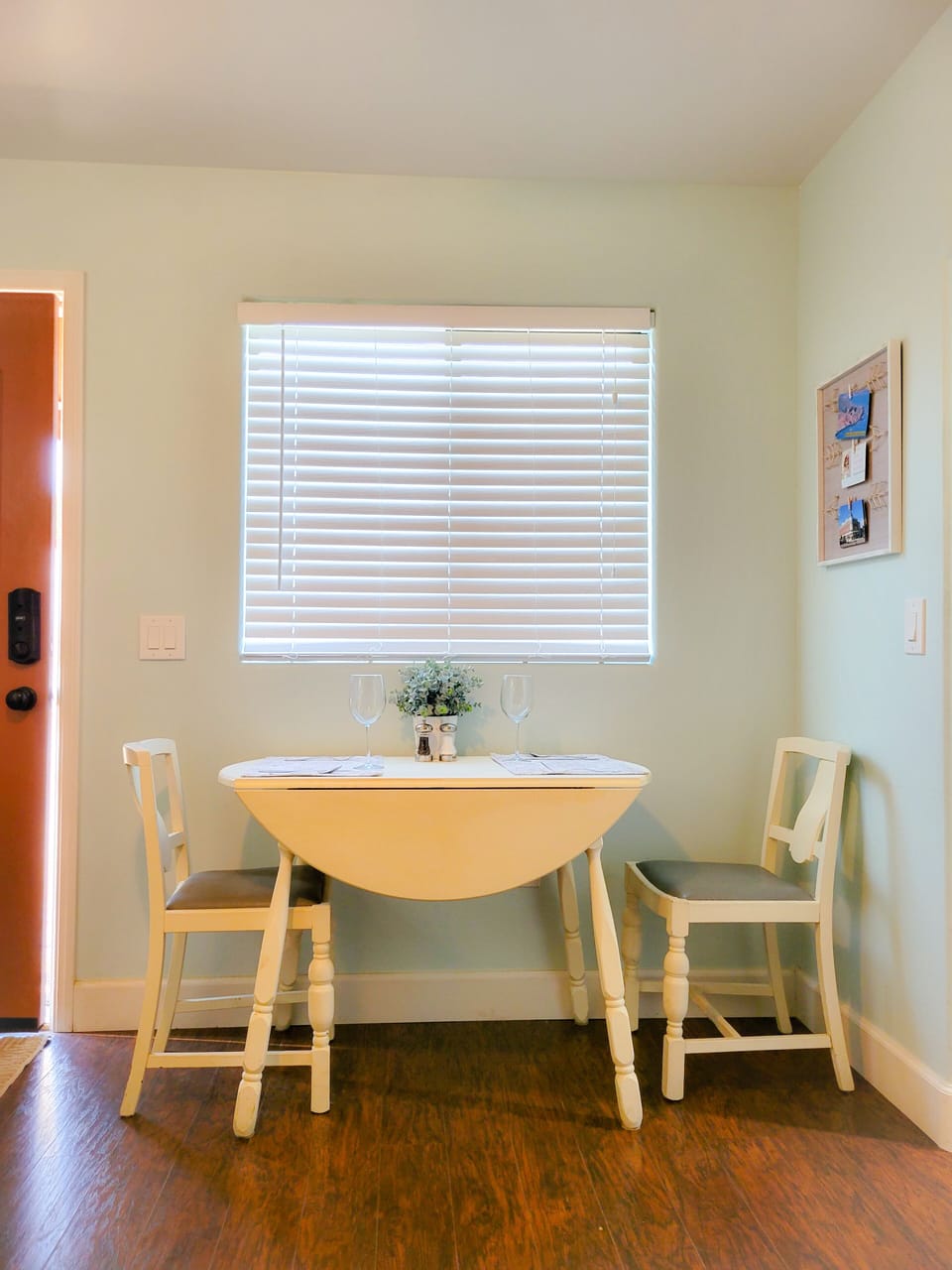 Small dining nook set for two by a window with blinds.