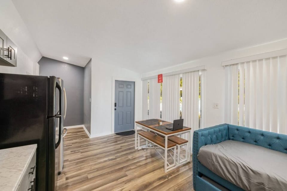 This shared room includes a kitchen with functional cabinets and a large refrigerator. It also features a small dining area.