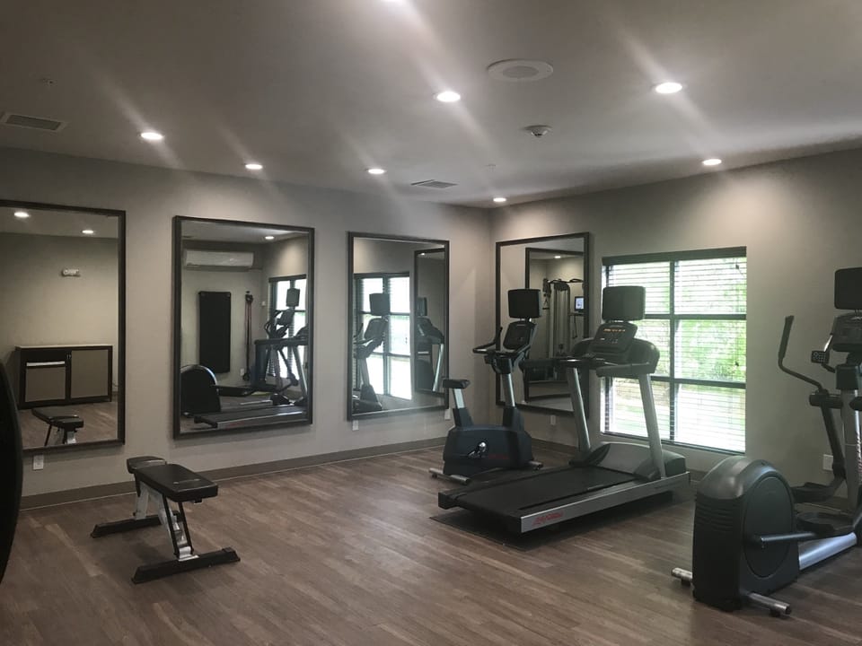 Fitness room with workout machines and weight racks.