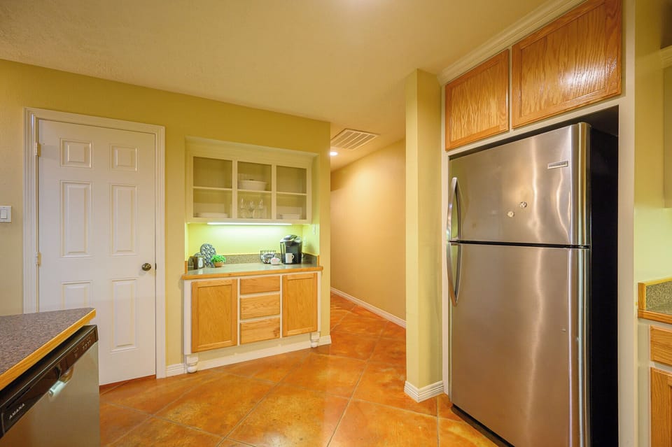 This view of the kitchen features the fridge and coffee bar.
