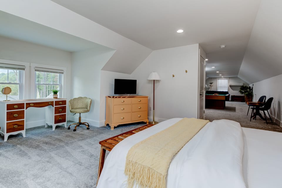 Spacious upstairs bedroom with a queen bed, dresser, and peaceful natural light