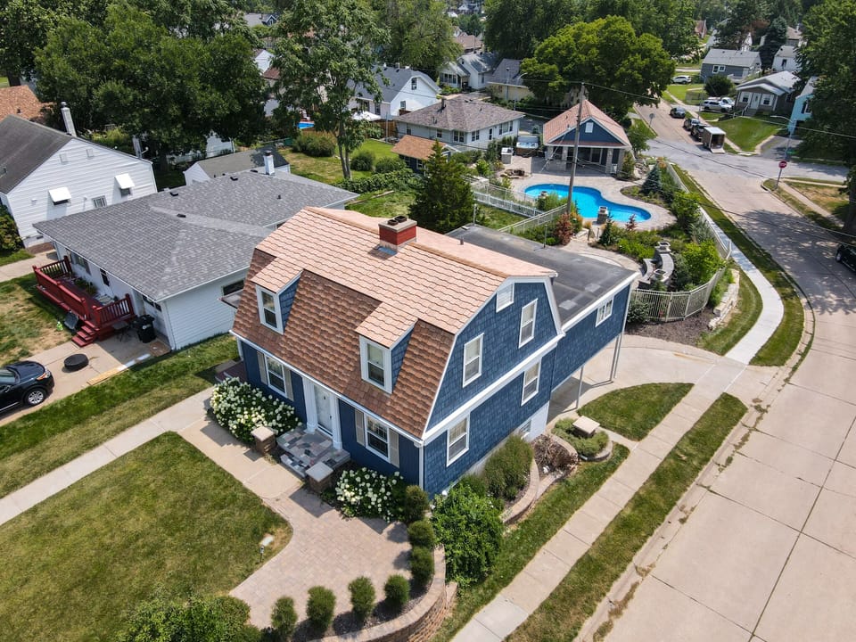 Charming blue Cape Cod-style home nestled in a peaceful residential neighborhood with tree-lined streets and well-maintained gardens.