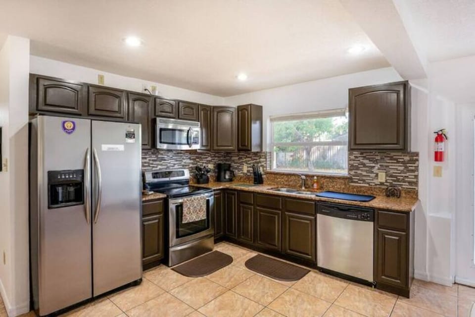 Kitchen equipped with refrigerator, stove with oven, microwave, dishwasher, sink, coffee maker, kitchen cabinets, outside window