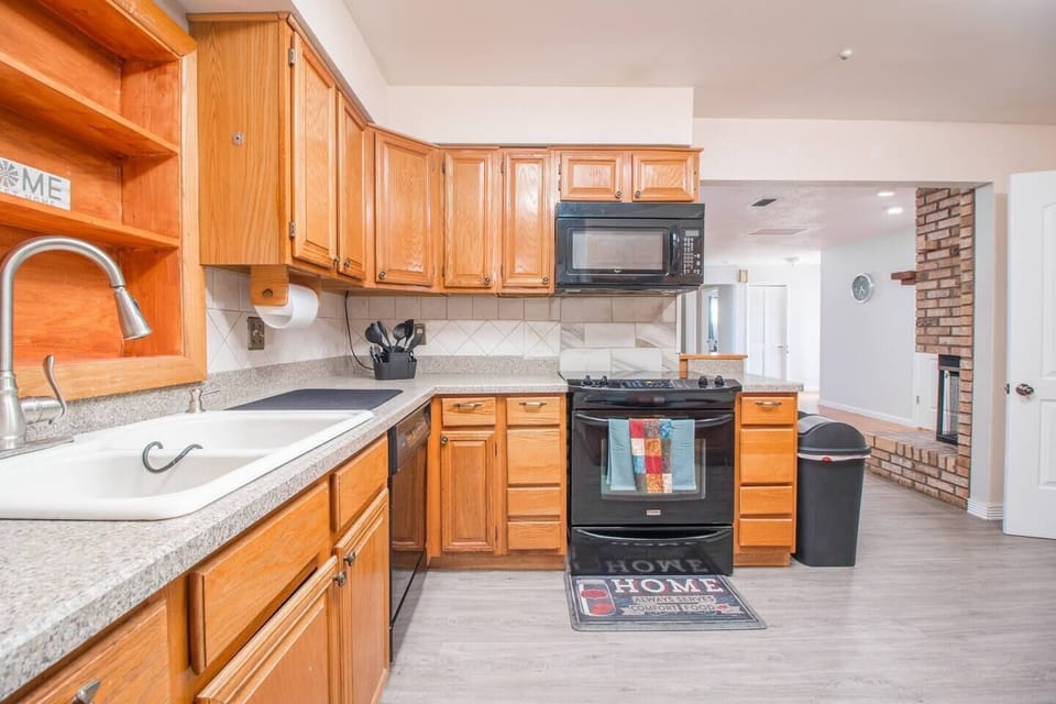 Range with oven, microwave, storage cabinets, trash can and access doors