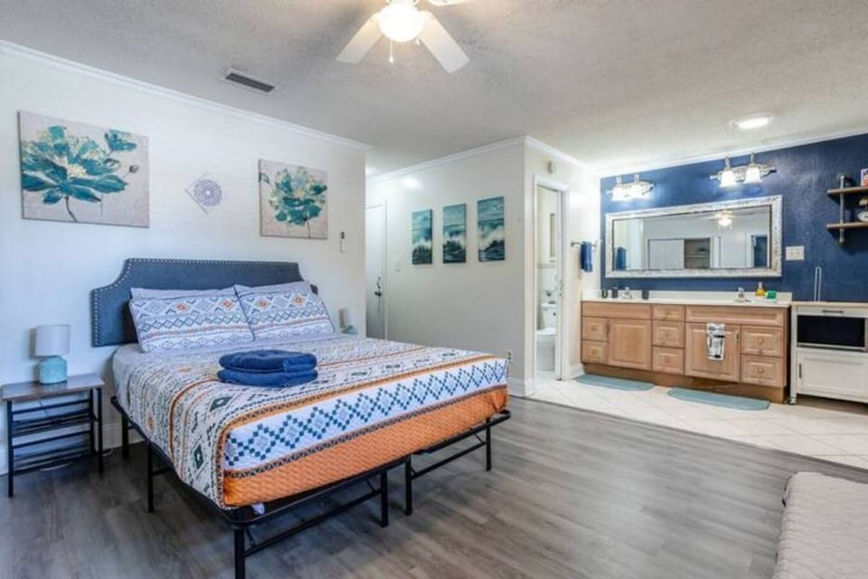 A comfortable bed. To the right, the bathroom features a functional design, a large mirror, and a spacious shower.
