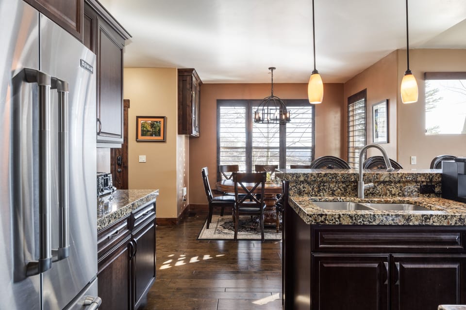 - Kitchen with stainless steel appliances and granite tops  
- Pendant lights brighten the space with warm tones  
- Dining area nearby offers seating with mountain views