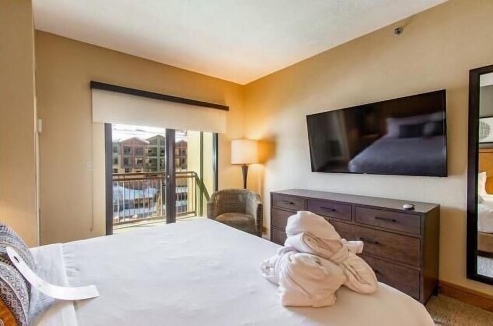 Spacious king bedroom with a large TV, dresser storage, and direct access to the private balcony.