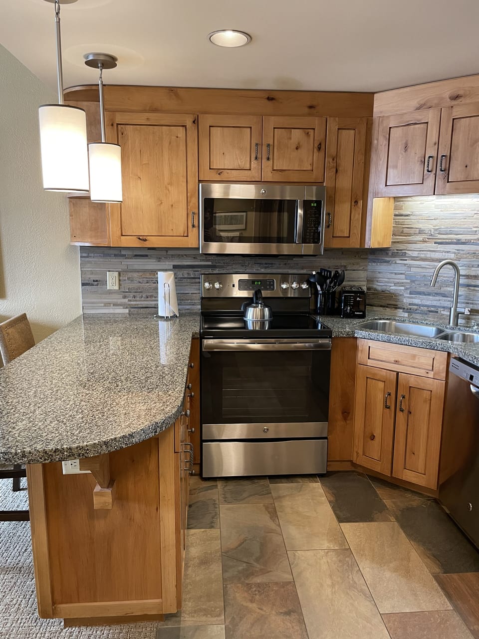 Fully equipped kitchen with granite countertops, stainless steel appliances, and bar seating for casual dining.