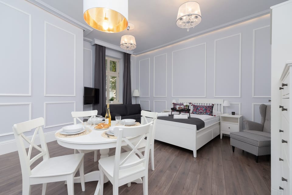 A wider view of the dining and sleeping area, showcasing clean lines and white furniture.
