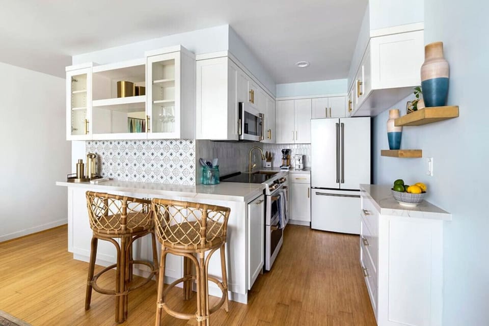 Fully stocked and pristine kitchen featuring modern fixtures, high-end appliances, and all the essentials needed for a seamless cooking experience, with seating for two—perfect for enjoying a morning coffee or a casual meal.