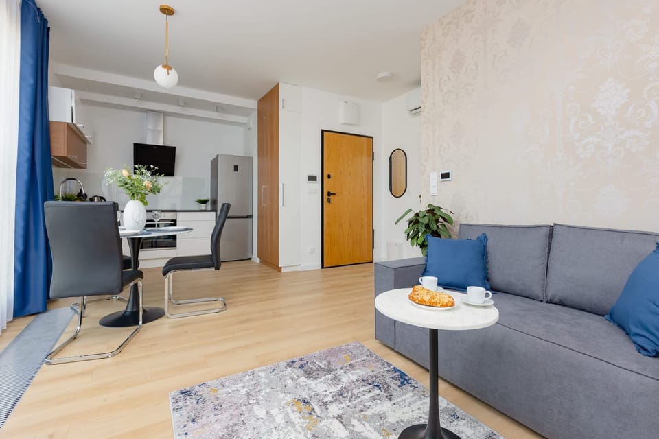 A wide-angle view of the living area connected to the kitchen, styled with blue curtains and comfortable furniture.
