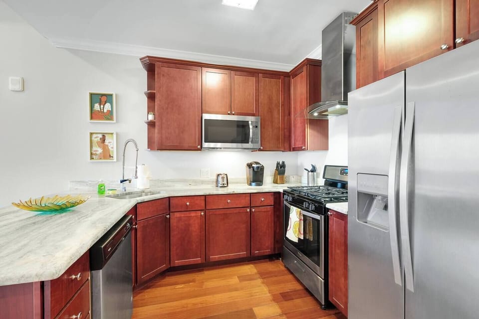Modern kitchen with  stainless steel appliances including full-size refrigerator and range.