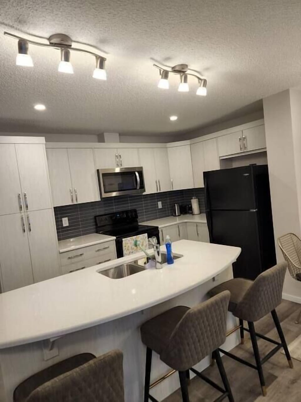 A full kitchen with all essentials, Microwave, refrigerator, sink and a Gas station