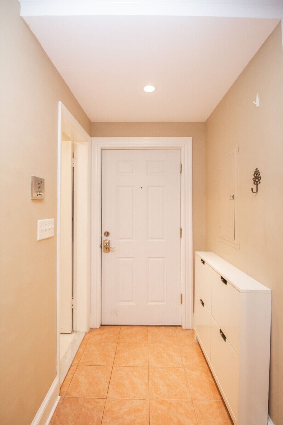 Welcoming entryway with neutral walls, tiled floors, and a sleek storage unit.